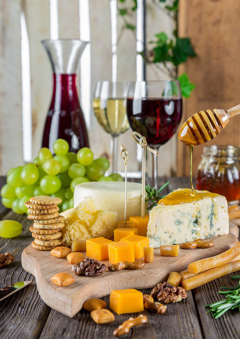 Cheese board with crackers, nuts, honey, and wine